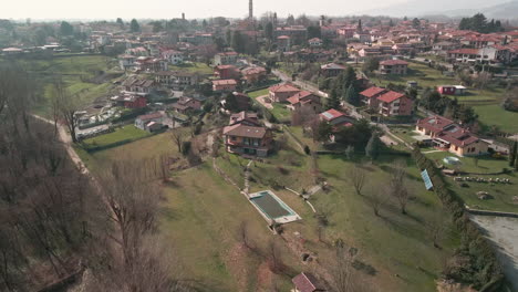 Residential-Houses-In-The-Countryside-Surrounded-By-Green-Meadows-And-Trees-In-Northern-Italy---aerial-drone-shot