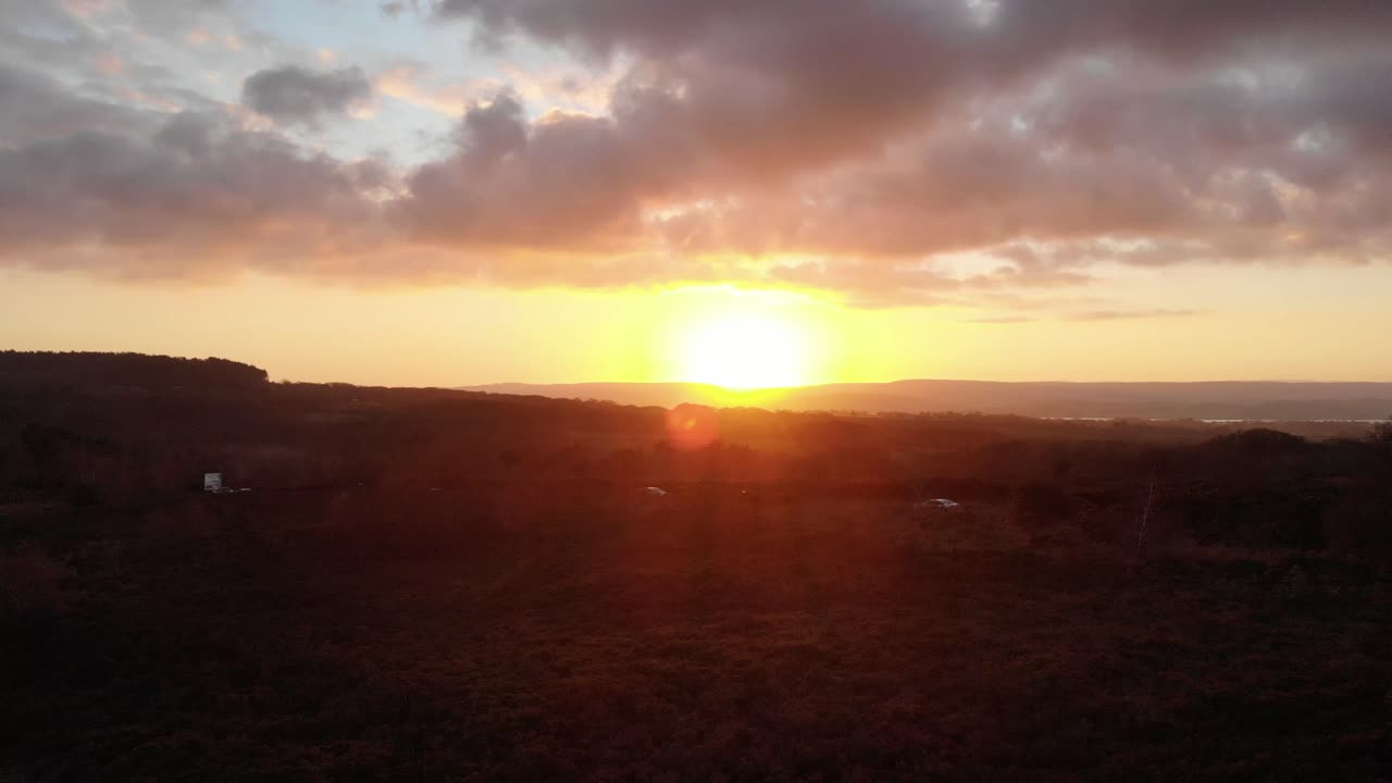 Rising aerial shot looking over busy road near Exmouth in Devon England with golden sunset in the background
