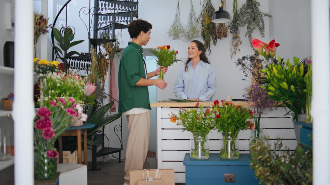 미소 짓는 꽃 판매자는 꽃 가게에서 아프리카 구매자에게 꽃을 판매합니다. 꽃 개념