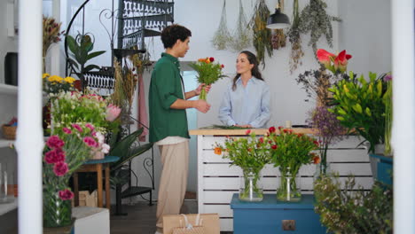florista sonriente vende flores al comprador africano en la tienda de floristería. concepto floral