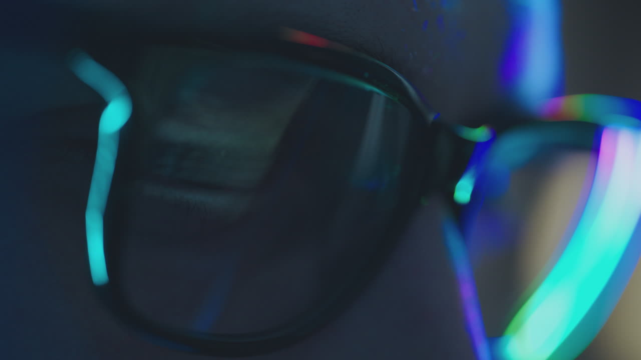 Close-up of a person wearing glasses reflecting code at night.
