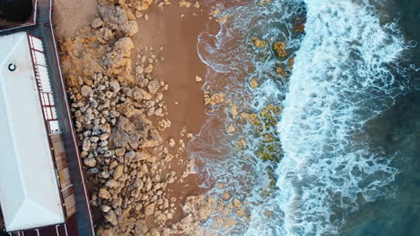 aerial footage capturing the unyielding force of sea waves crashing against the rugged coastal expanse of portugal