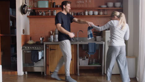 Feliz-Pareja-Joven-Bailando-En-La-Cocina-Disfrutando-De-Un-Divertido-Baile-Juntos-Divirtiéndose-Celebrando-La-Relación-El-Fin-De-Semana-En-Casa