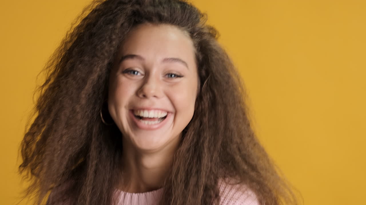 sorprendida mujer caucásica de cabello rizado sonriendo a la cámara.