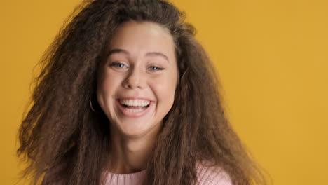 sorprendida mujer caucásica de cabello rizado sonriendo a la cámara.