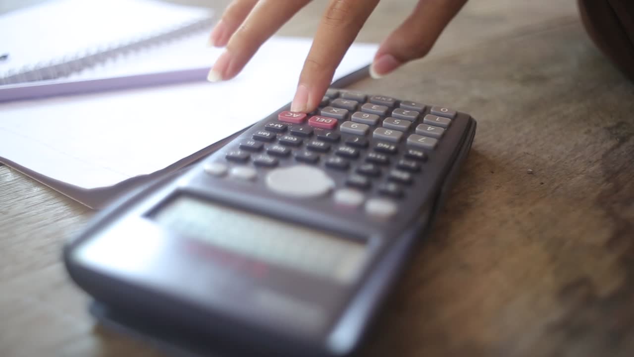 Business woman's hands using calculator and Financial data analyzing on wooden desk at the office