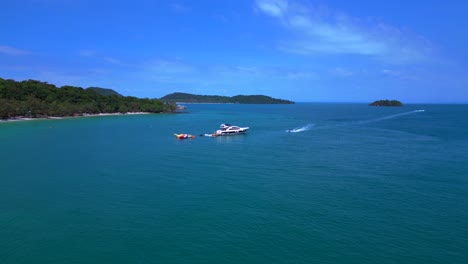 tourists enjoying summer vacation on a luxury yacht with inflatable games and jet skis. magic aerial view flight