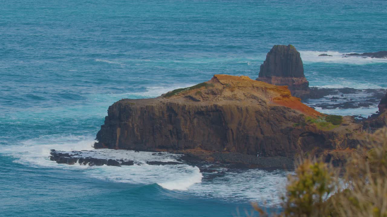 Steady telephoto shot of rugged coastline, ocean waves, and dramatic cliffs under diffuse daylight
