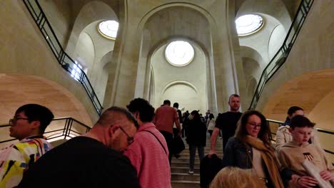 gente subiendo escaleras dentro del museo del louvre, parís