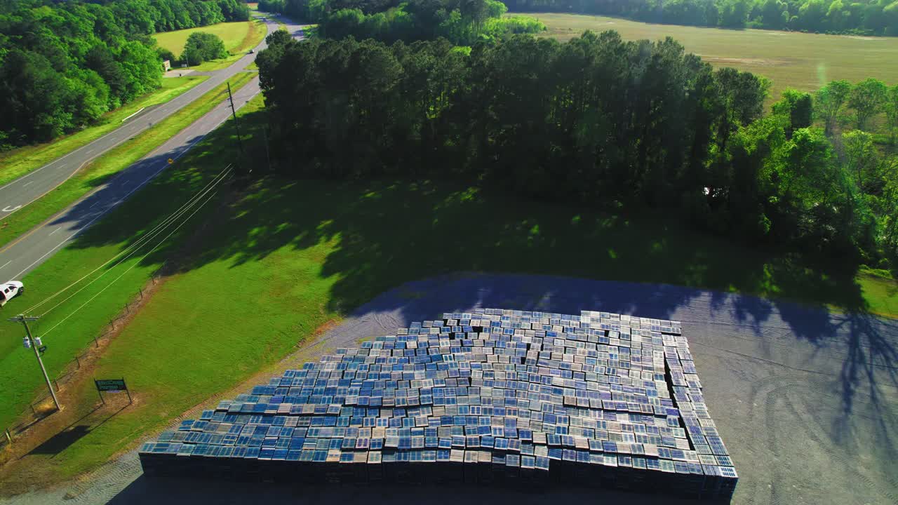 Aerial View of Massive Stacked Wooden Pallets Near Forested Roadside in Rural Georgia