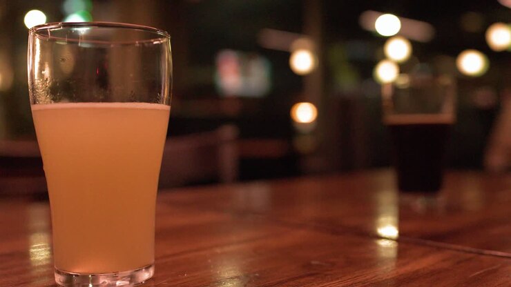 Un'inquadratura media statica di una pale ale su un tavolo di legno in un bar.