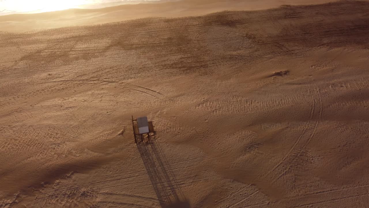 아르헨티나의 마르 데 라스 팜파스(mar de las pampas) 일몰 시 해변에 있는 인명 구조원 타워 주변을 공전하는 공중 하향식