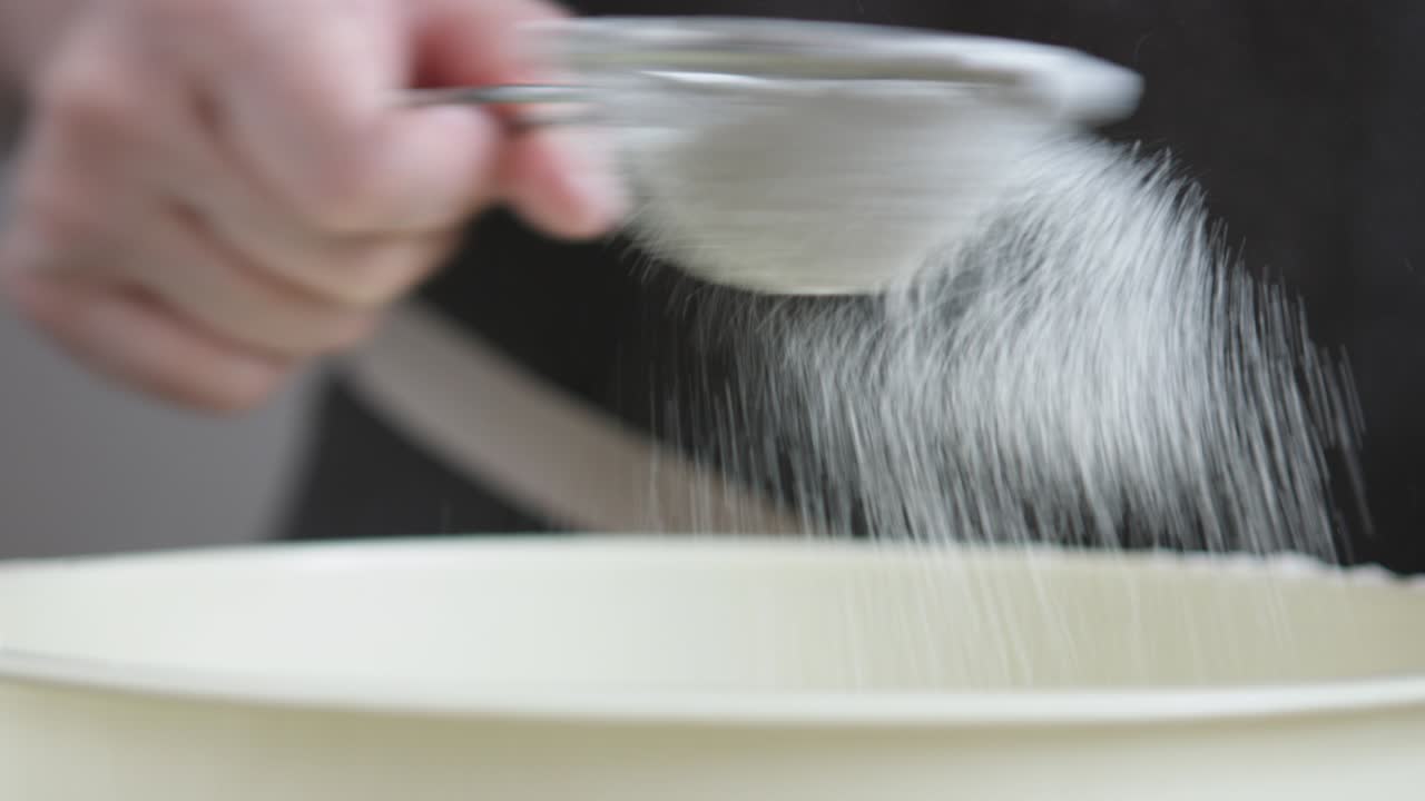 Female hands sifts the flour