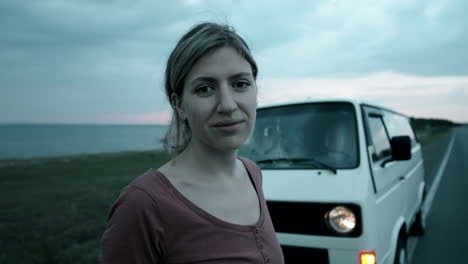 Portrait-of-Cheerful-Woman-Posing-for-Camera-by-Camper-Van