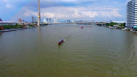 barco tradicional tailandés navegando en el río chao phraya con el puente rama viii en el fondo en bangkok, tailandia
