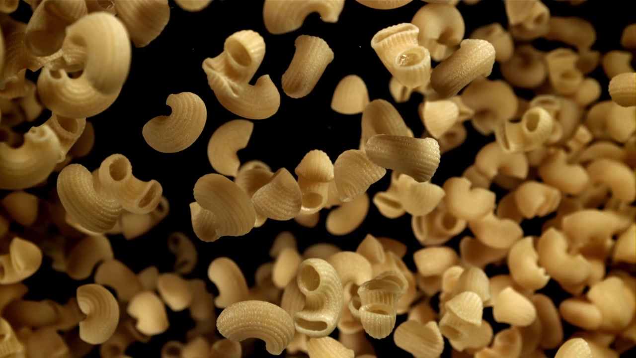 Pasta di maccheroni a gomito secchi che cadono al rallentatore