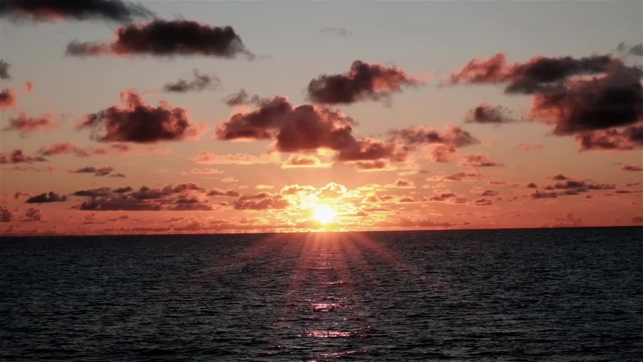Beautiful sunrise with solar flares over the ocean as seen from a moving boat