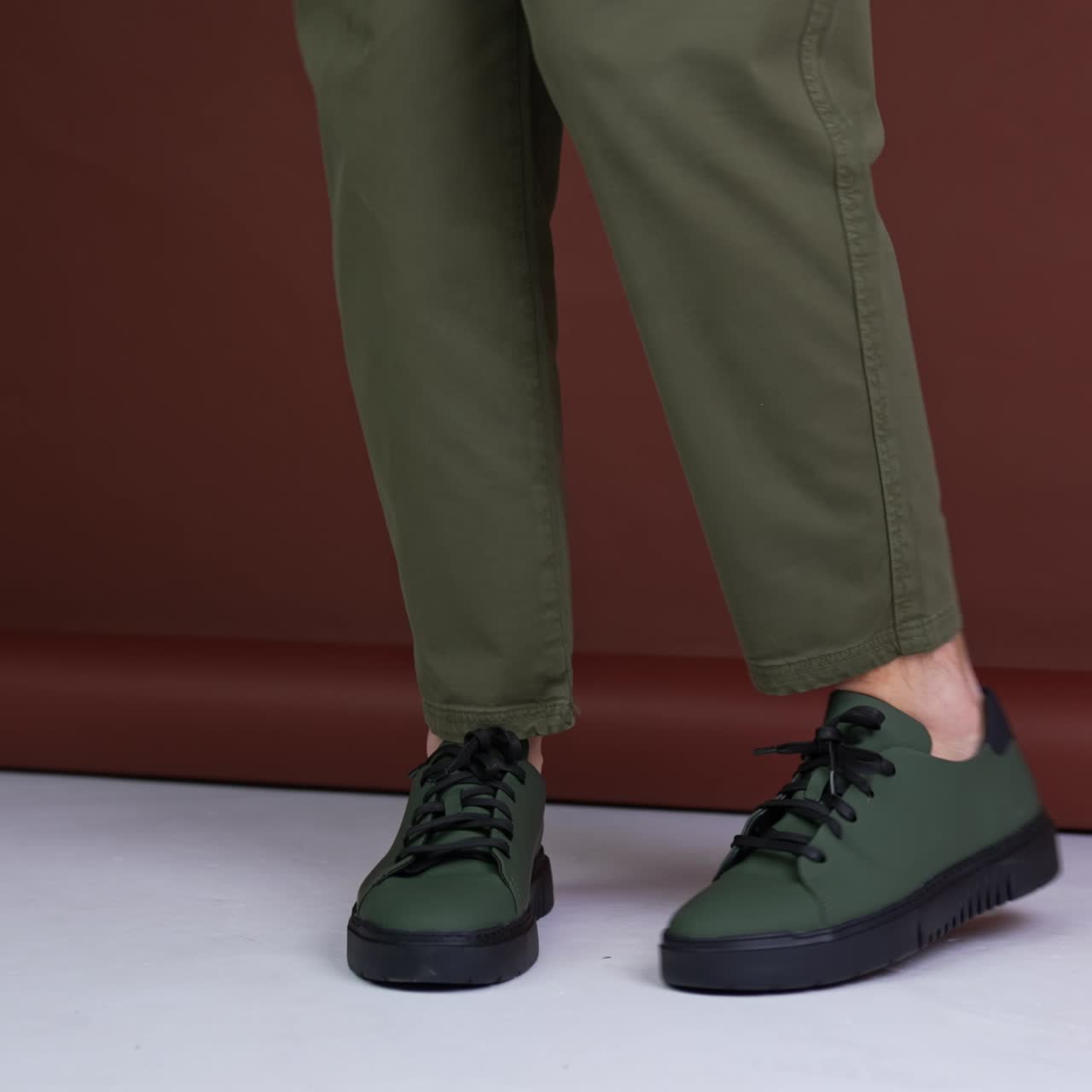 Male dancing and turning in front of camera demonstrating comfortable sneakers. Studio footage at brown backdrop