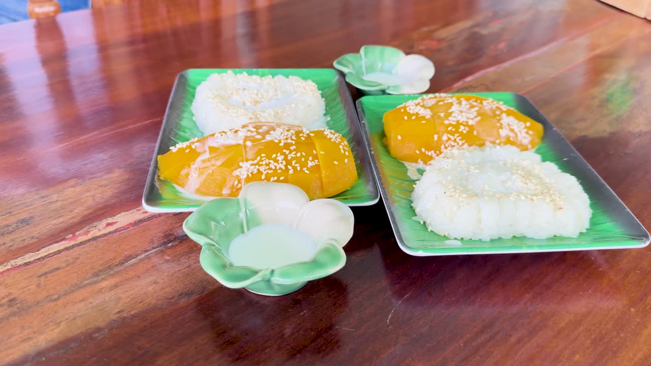 Mango sticky rice served on a wooden table in natural light at a Phuket restaurant. Vibrant colors and serene atmosphere