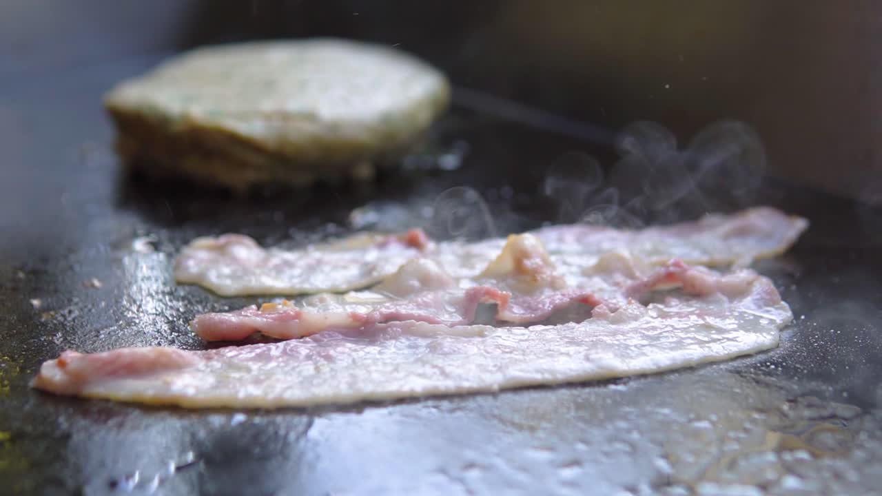 패스트푸드점에서 햄버거와 함께 그릴에 베이컨 요리하기