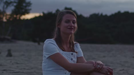 Attraktive-Junge-Frau,-Die-In-Der-Abenddämmerung-In-Wunderschönen-Sanddünen-Sitzt