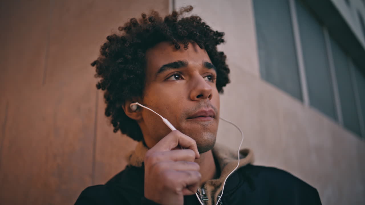 Handsome teenager talking headphones in urban setting closeup. Latin guy headset