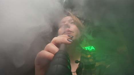 mujer fumando narguile en una habitación oscura con luz de neón verde