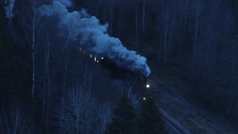 aerial shot of steam train rolling through the night winter forest