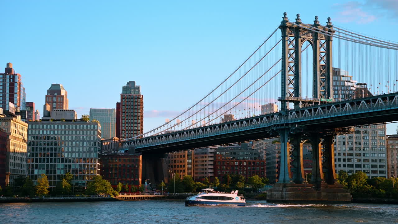 Motoscafo turistico bianco che passa sotto il Ponte di Manhattan a New York. Traghetto turistico sull'East River con il Ponte di Manhattan e gli edifici della città all'ora d'oro.