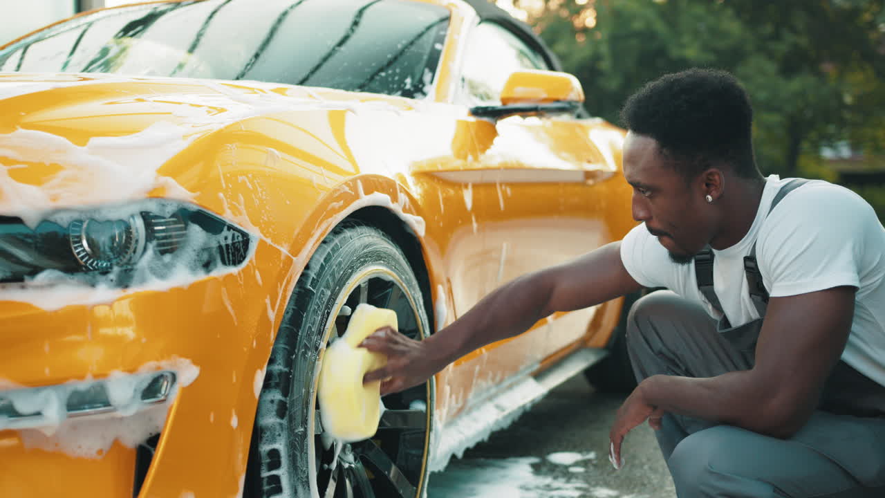 hombre lavando un coche descapotable amarillo