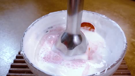 beaten eggs with sugar and strawberries using a mixer.slow motion with rotation tracking shot.