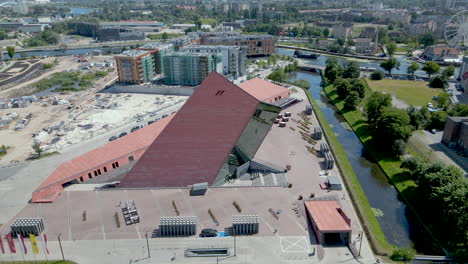 Aerial-orbit-shot-of-modern-Second-World-War-Museum-in-Gdansk-during-sunny-day-beside-residential-complex-and-river