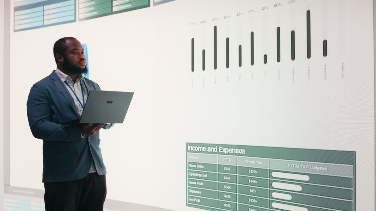 African American Businessman Analyzing Financial Data on Large Screen with Laptop