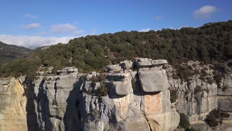 Aerial-view-of-man-standing-on-edge-of-projecting-cliff,-zooming-out-shot