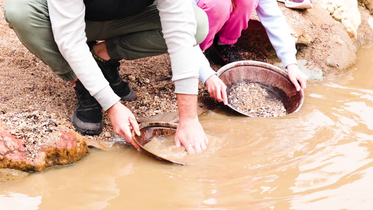 dos personas buscando oro en el agua