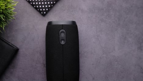 hand touching the power button of a black portable speaker