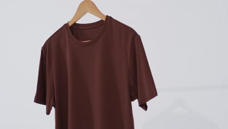 video of brown t shirt on hanger and copy space on white background