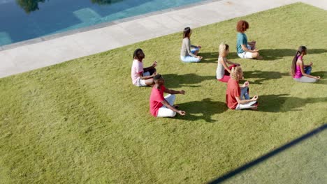 vista de alto ángulo de diversos amigos practicando meditación de yoga sentados en un jardín soleado, cámara lenta