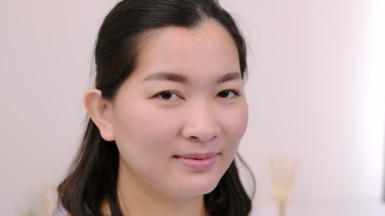 아름답고 웃고 있는 아시아 여성들은 휴일에 혼자 전문적인 초상화를 취한 카메라를 바라보며 극도로 자신감 있는 젊은 얼굴을 하고 맑은 빛, 슬로우 모션 장면으로 휴식을 취합니다.