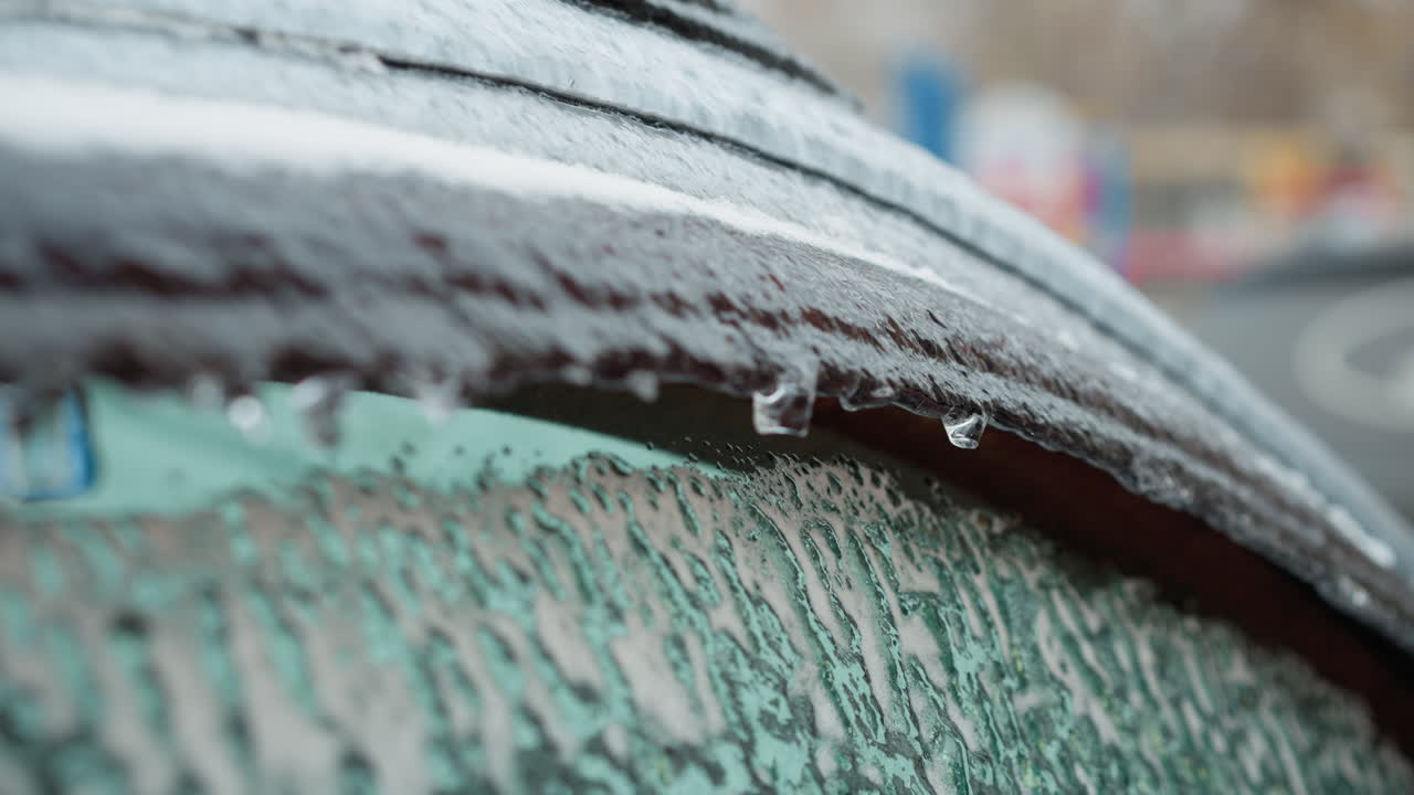 녹는 얼음 조각, 흐릿한 다채로운 배경, 텍스처 대조와 겨울 풍경의 생생한 추위를 강조하는 얼음 차량 창의 클로즈업