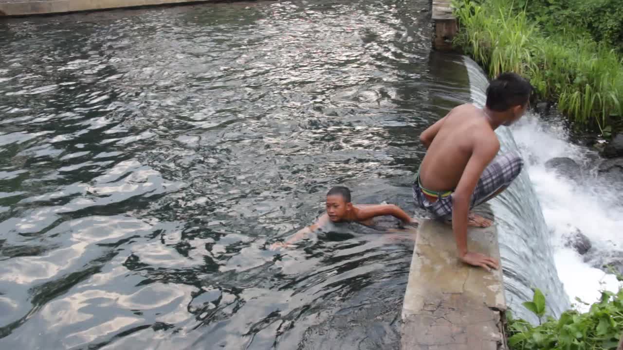 Umbulan baths, Pasuruan-Indonesia. January 2020. young people are playing in a clear and fresh water source. holiday footage playing nature water