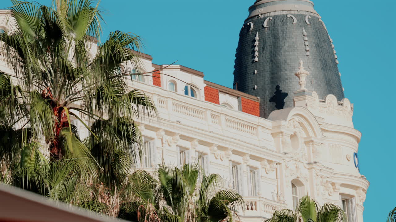 Beautiful facade of a historic luxury hotel framed by palm trees against a clear blue sky