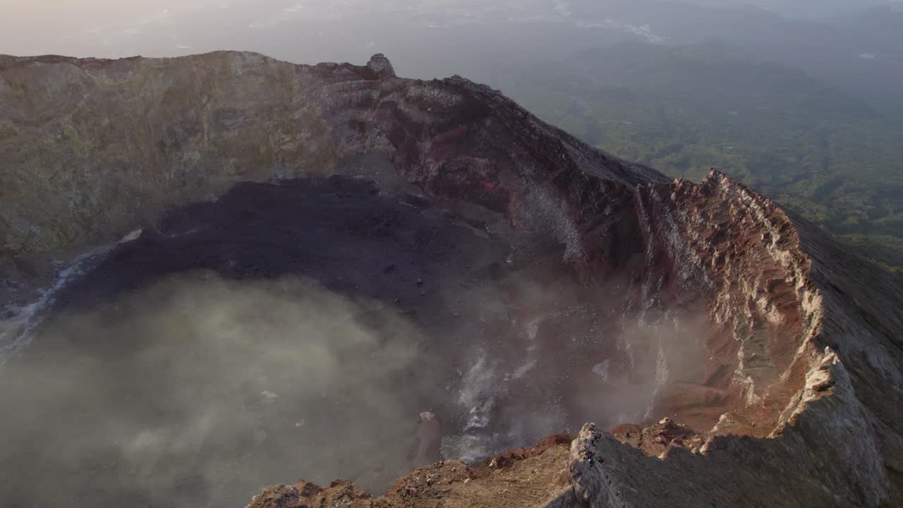 Cratere vulcanico attivo con fumo vorticoso e aspre pareti interne, orbita aerea interna del Monte Agung in Indonesia.