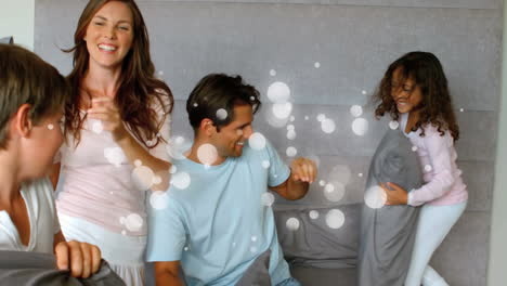 happy family having pillow battle in bedroom with light effect