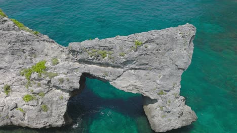 rock arch cliff surrounded by shallow blue turquoise water, aerial