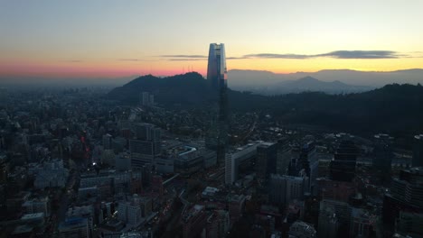 Aerial-fly-Santiago-de-Chile-city-sunset-skyline-high-downtown-Andean-cordillera-dusk-in-golden-hour