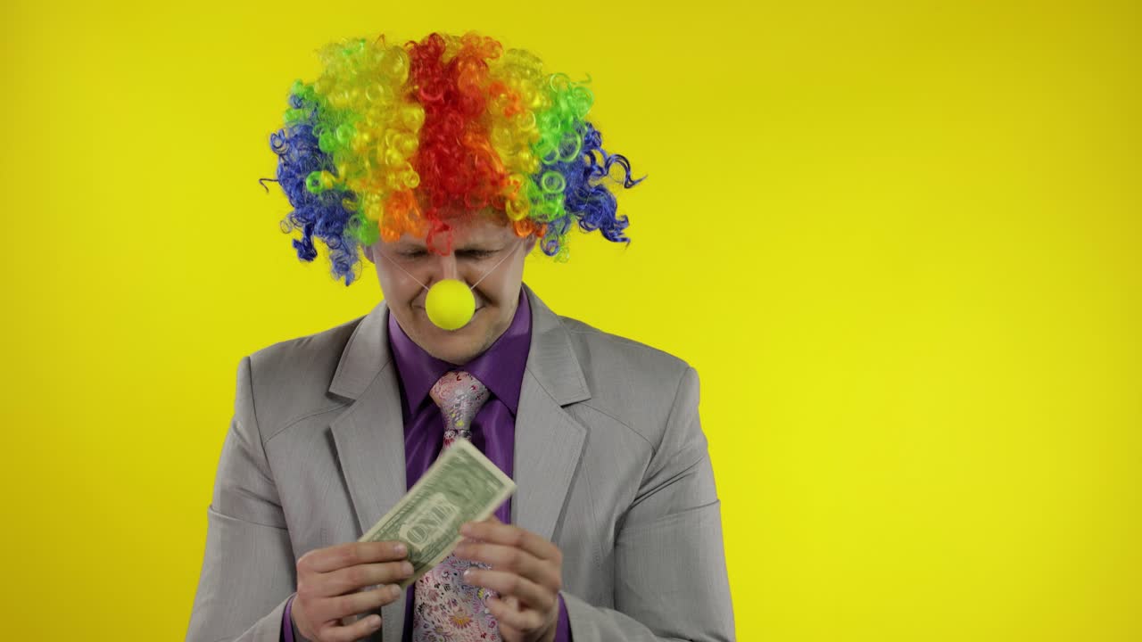 Clown businessman entrepreneur in wig holds one buck money income and loses it