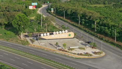 Huge-city-entrance-sign-on-highway-to-San-Pedro-de-Macoris,-aerial-orbit