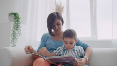 retrato de un niño lindo leyendo un libro con su madre mientras está sentado en la caja fuerte