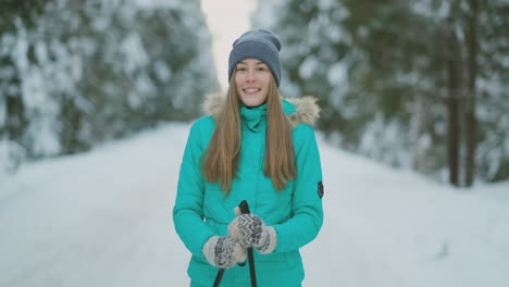 Waist-up-portrait-of-beautiful-young-woman-smiling-happily-looking-at-camera-while-enjoying-skiing-in-snowy-winter-forest,-copy-space